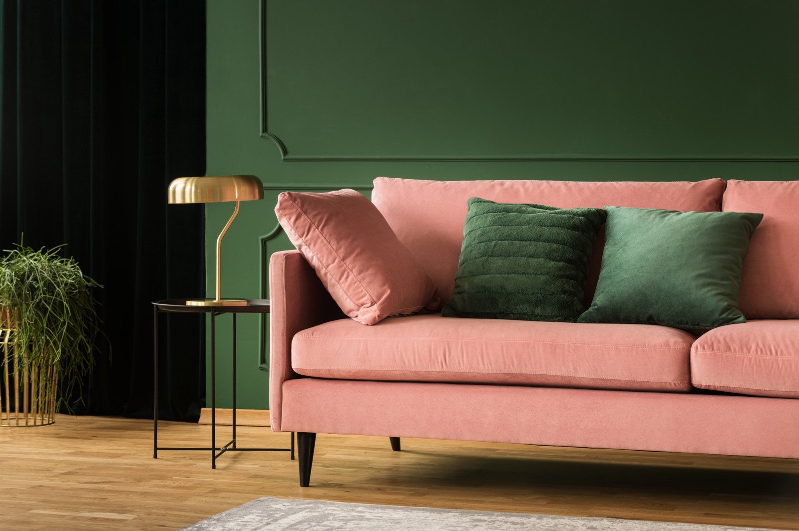 różowa kanapa na tle zielone ściany
